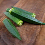 Fresh okra pods on a wooden surface.